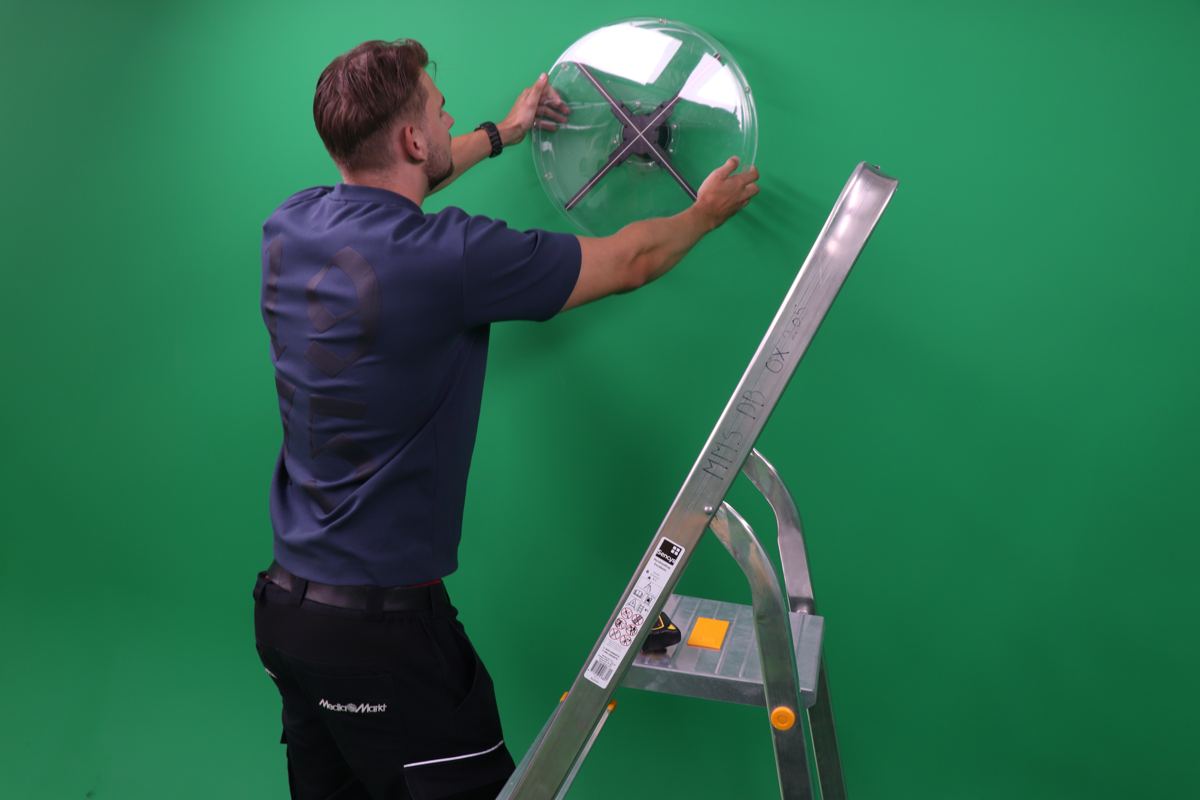 Een monteur hangt het hologram met beschermkap aan de muur